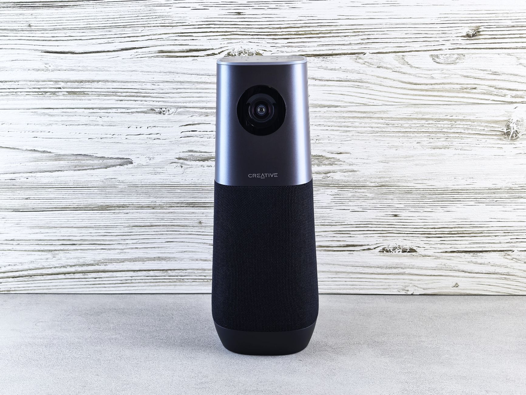 A sleek smart speaker with an integrated camera against a wooden backdrop, perfect for modern tech setups.