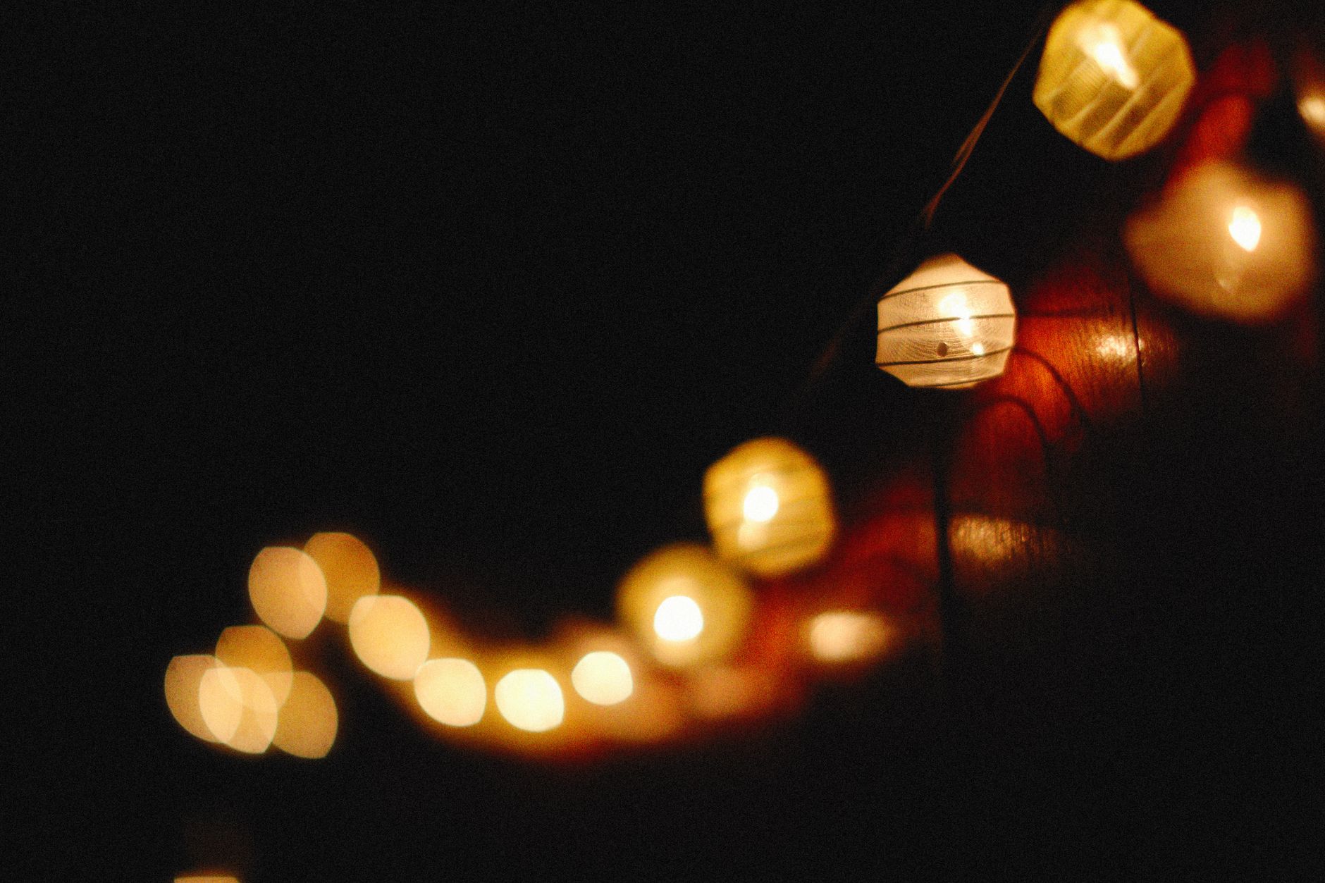 Close-up of glowing string lanterns against a dark background, creating a warm and cozy atmosphere.