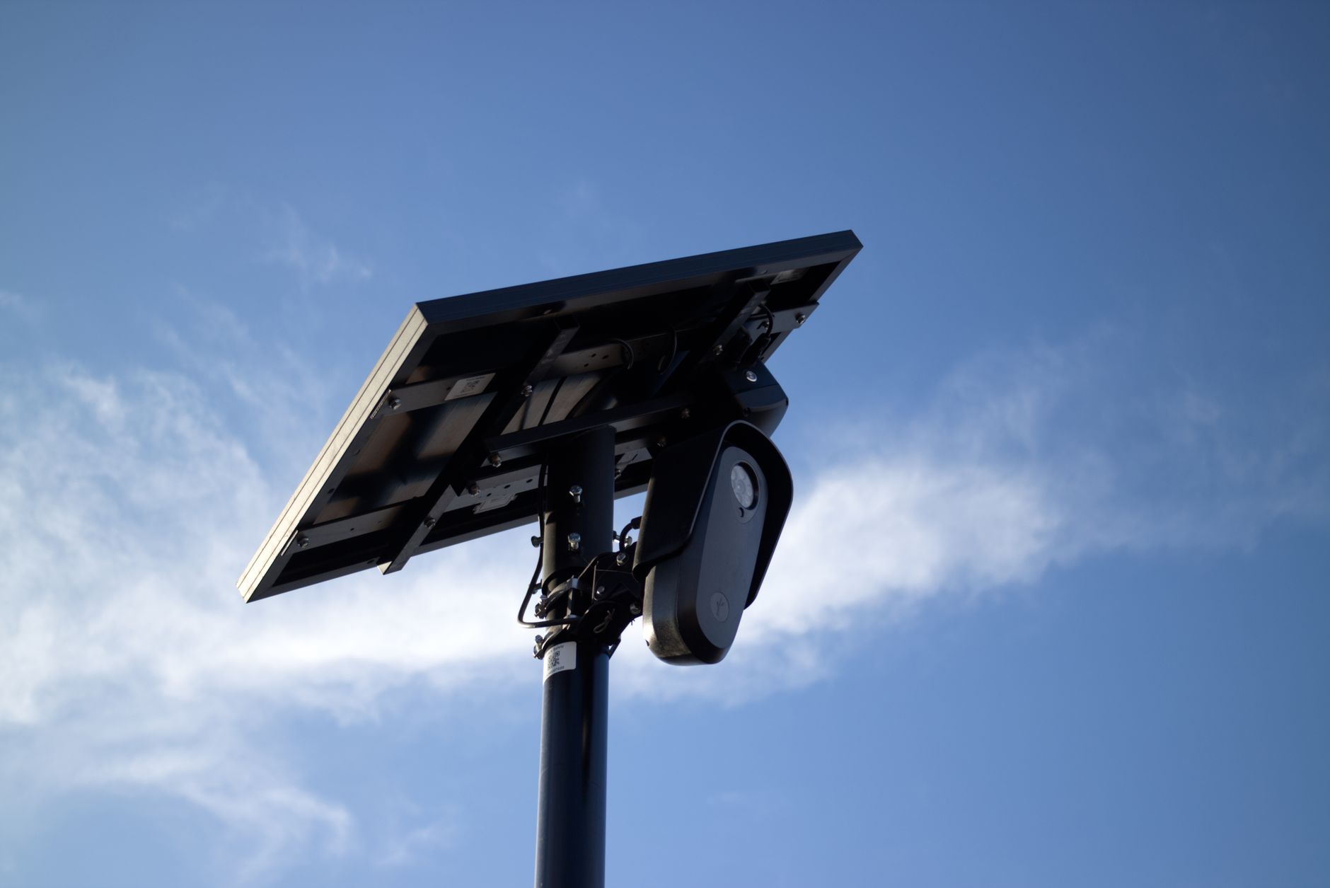 Solar-powered CCTV camera mounted on pole with bright sky background, symbolizing security and technology.