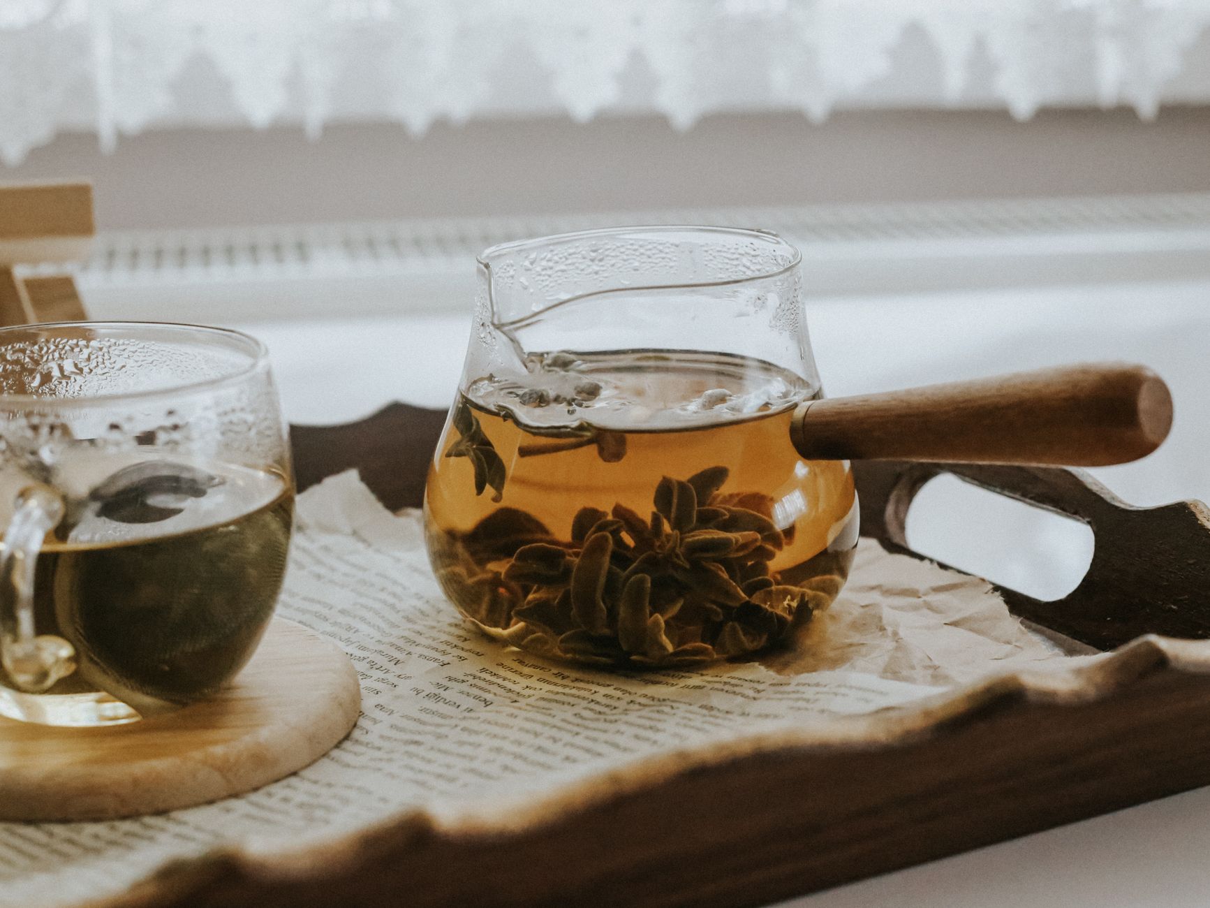 Elegant glass teapots with herbal tea served on a wooden tray, creating a cozy morning vibe.