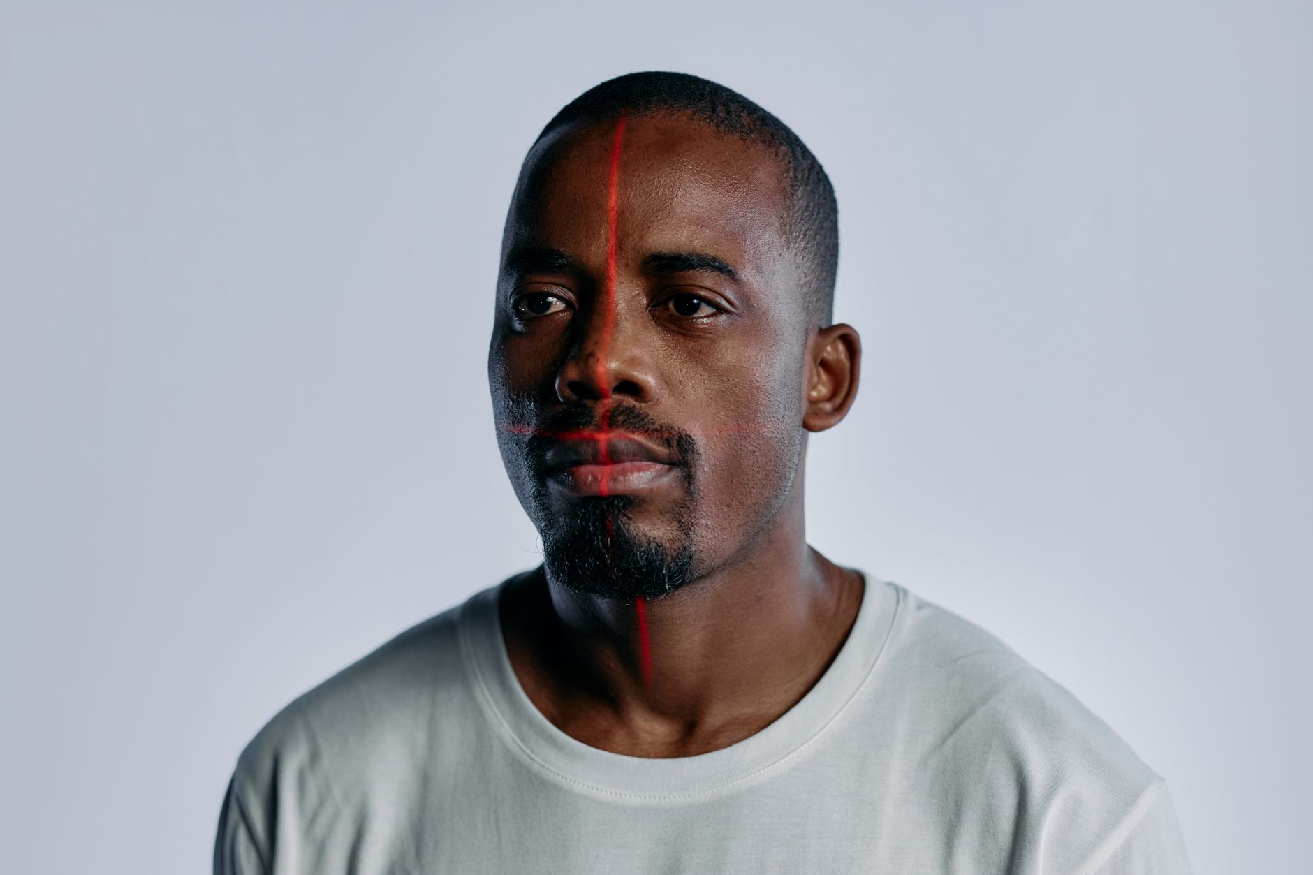 Portrait of an adult man with laser grid on face in studio setting, symbolizing high-tech facial recognition.