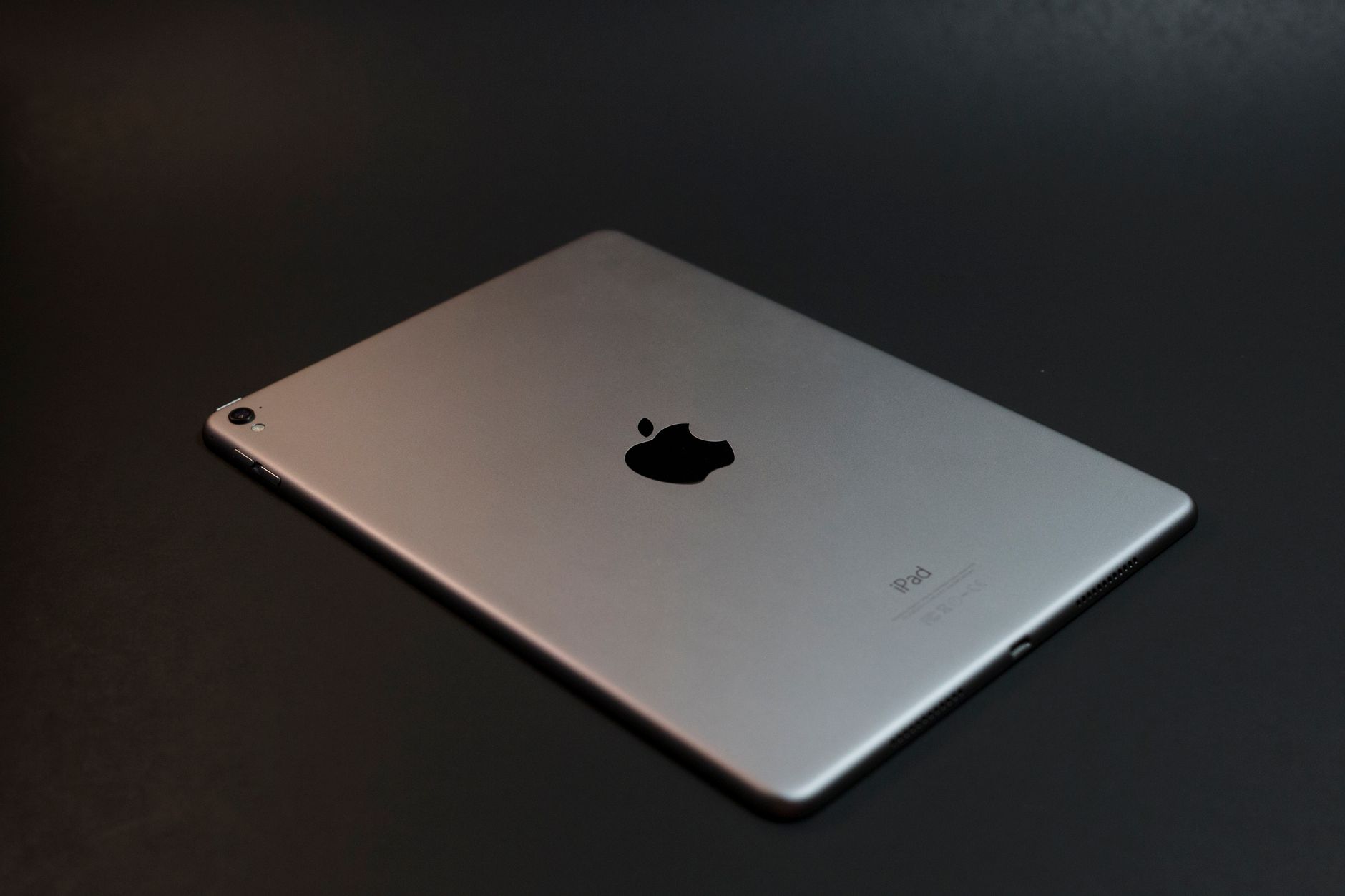 A modern silver tablet with a sleek design on a dark surface, showcasing advanced technology.