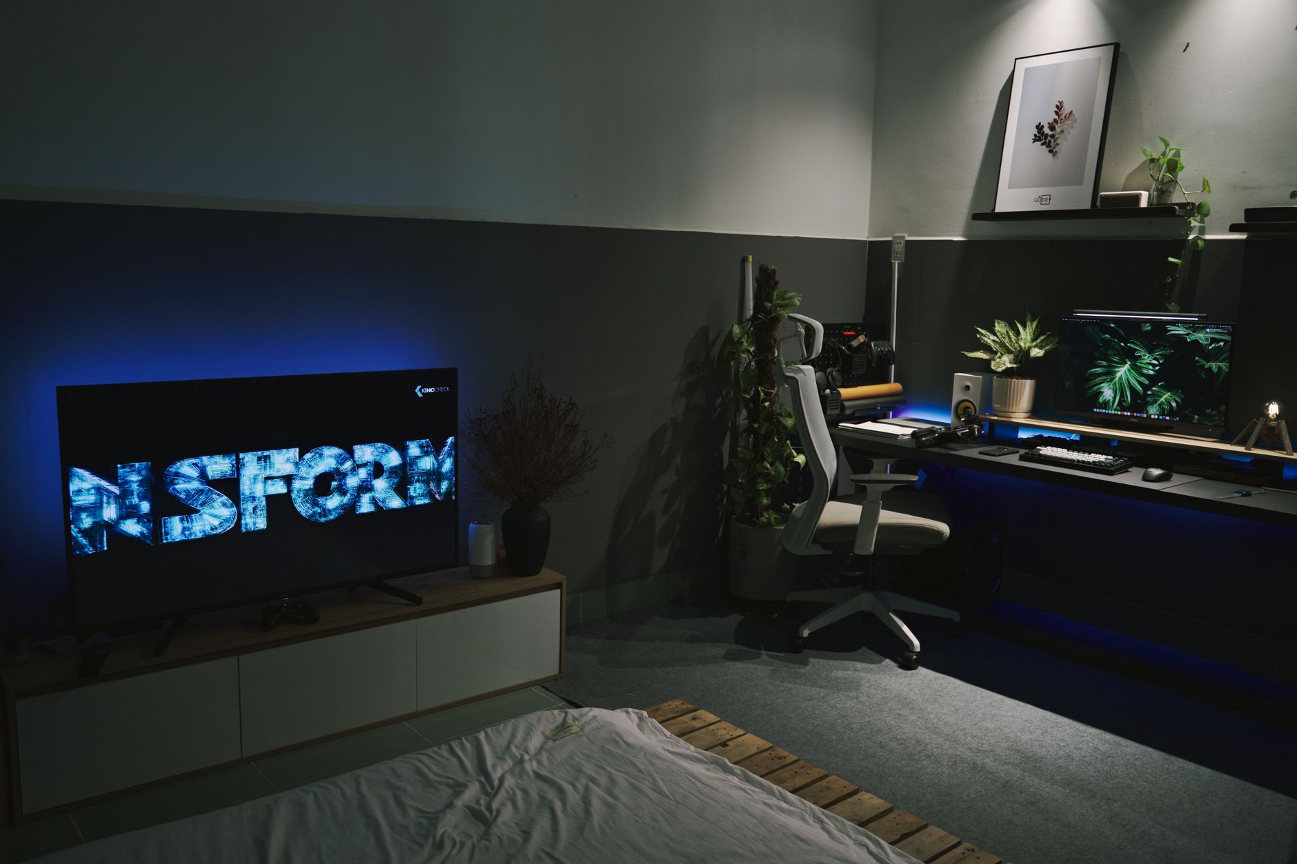 A sleek gaming room featuring a dark, contemporary setup with ambient blue lighting and multiple screens.