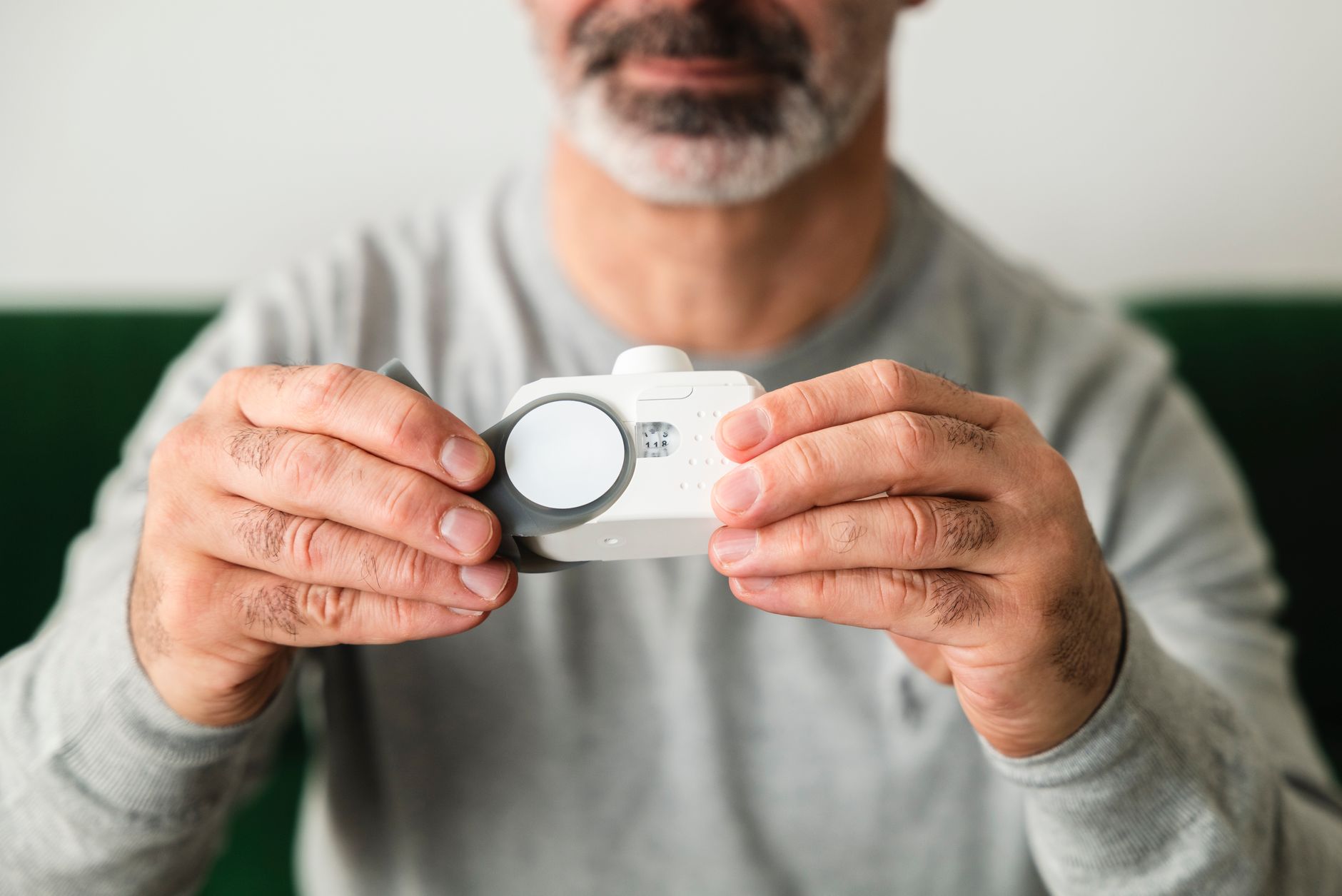 A close-up of a man using a handheld air quality analyzer, focusing on health and technology.