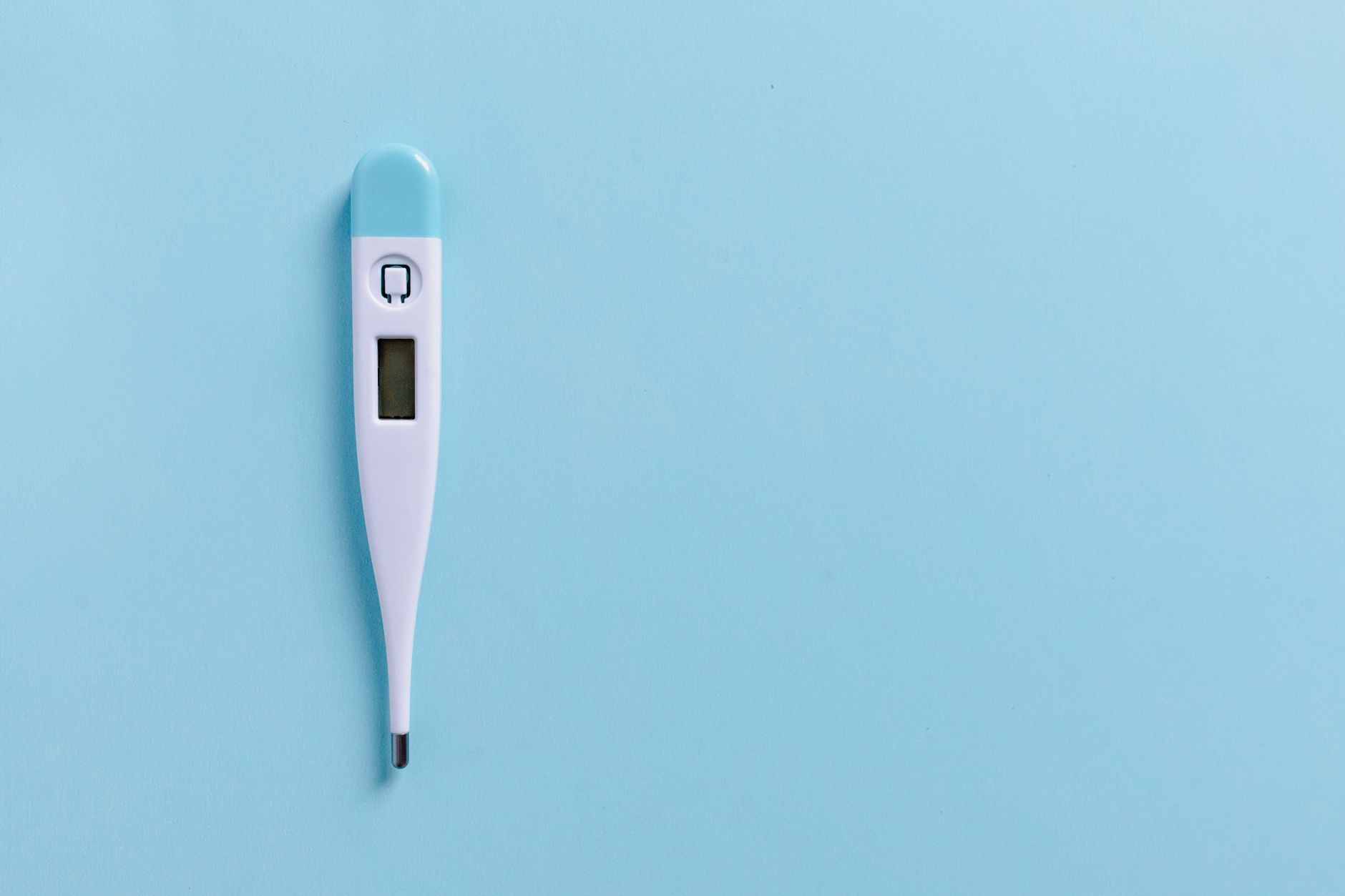 Close-up of a digital thermometer on a light blue background with copyspace.